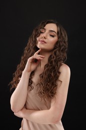 Photo of Beautiful young woman with long curly brown hair on black background