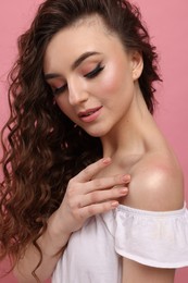 Photo of Beautiful young woman with long curly brown hair on pink background