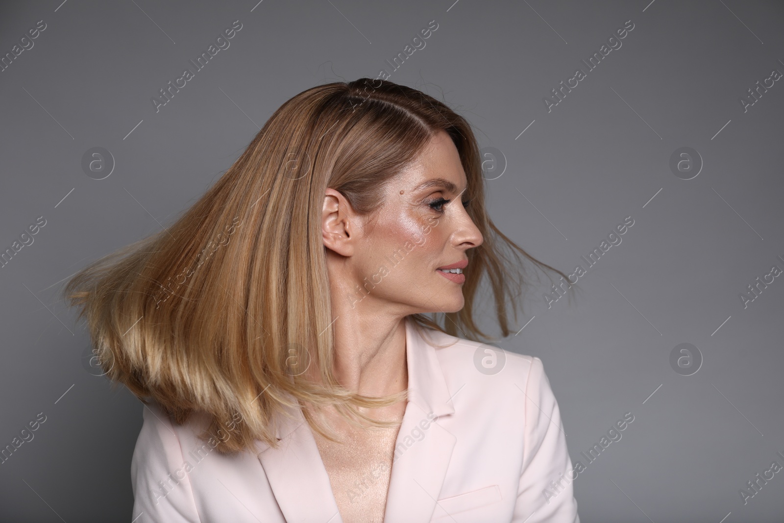 Photo of Portrait of beautiful woman with straight blonde hair on grey background