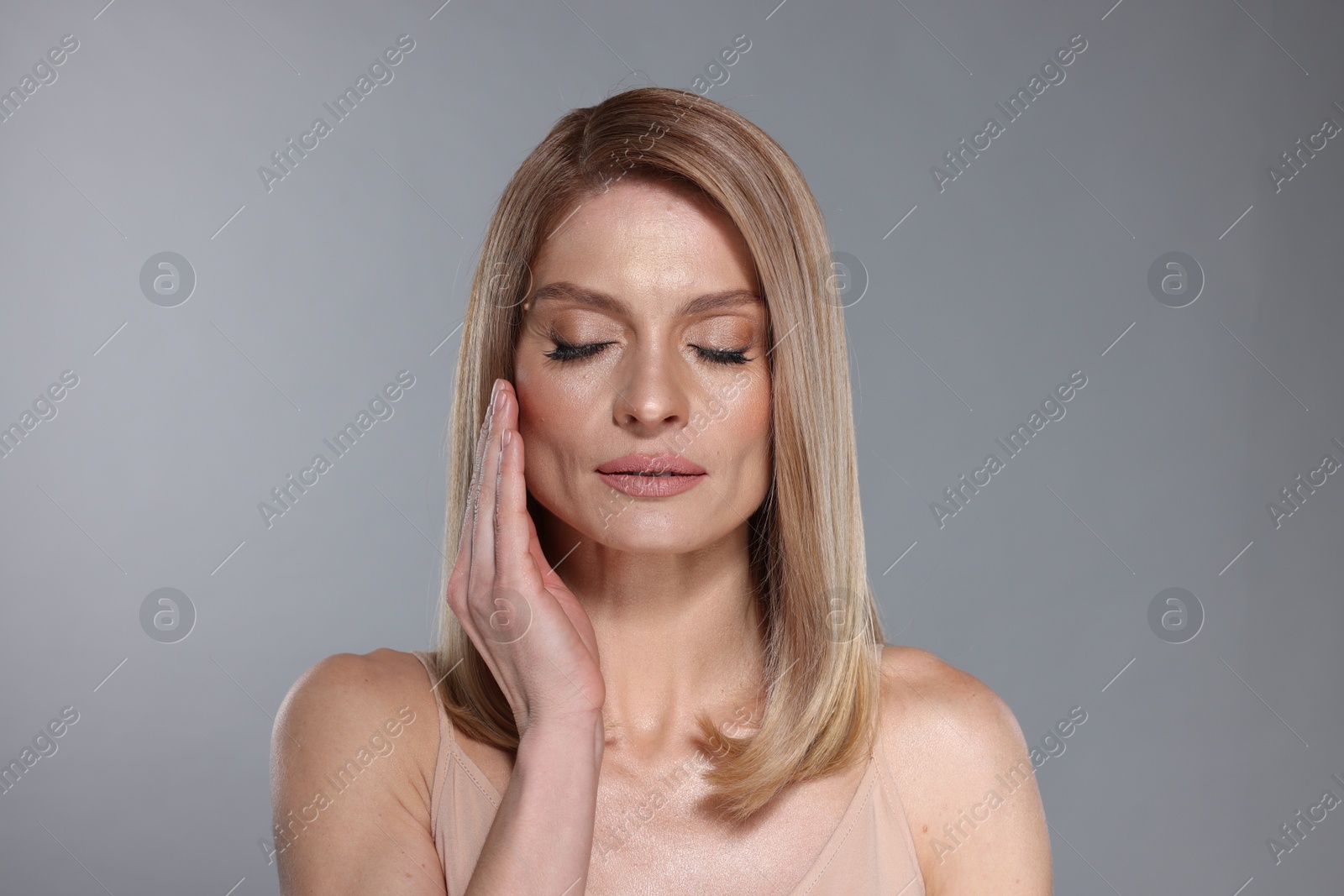 Photo of Portrait of beautiful woman with straight blonde hair on grey background