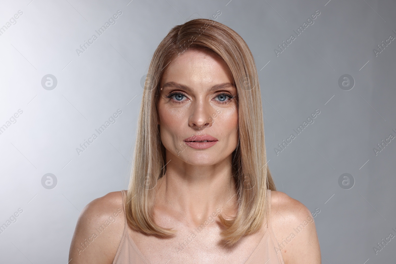 Photo of Portrait of beautiful woman with straight blonde hair on light grey background