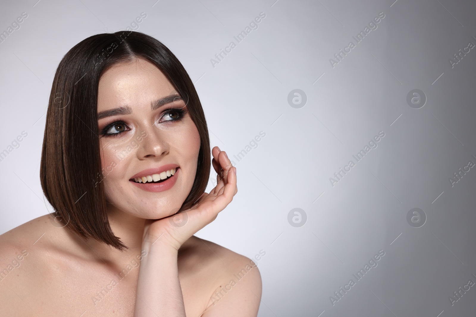 Photo of Portrait of beautiful young happy woman with gorgeous straight hair on light grey background, space for text