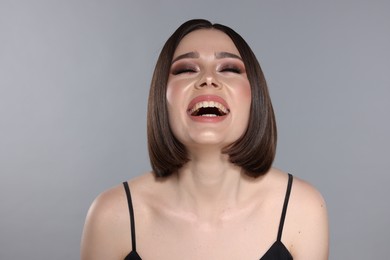 Photo of Portrait of beautiful young happy woman with gorgeous straight hair on light grey background