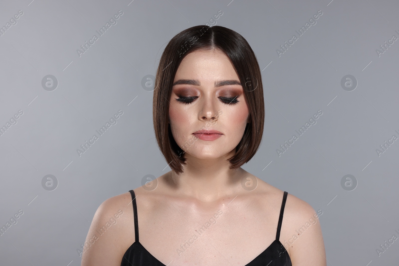 Photo of Portrait of beautiful young woman with gorgeous straight hair and stylish makeup on light grey background