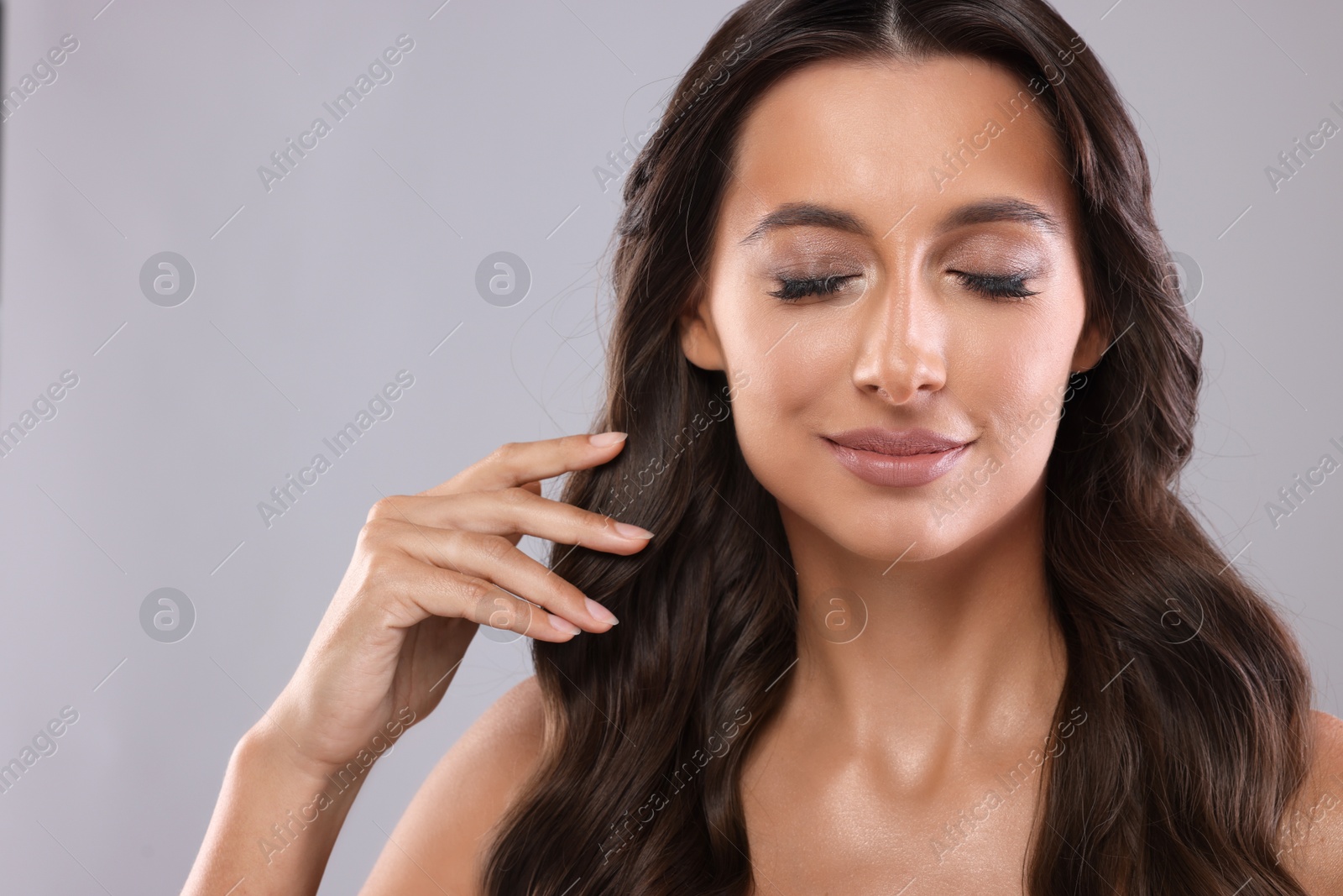 Photo of Hair styling. Beautiful woman with wavy long hair on grey background, closeup. Space for text