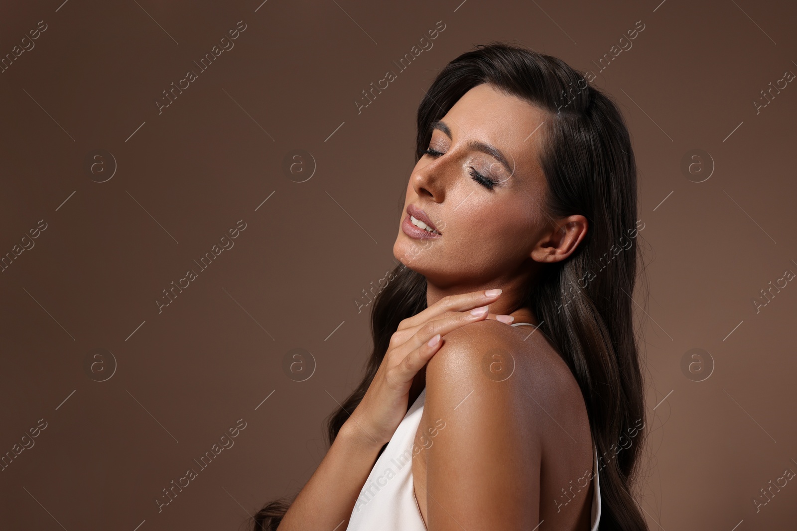 Photo of Hair styling. Beautiful woman with wavy long hair on brown background. Space for text