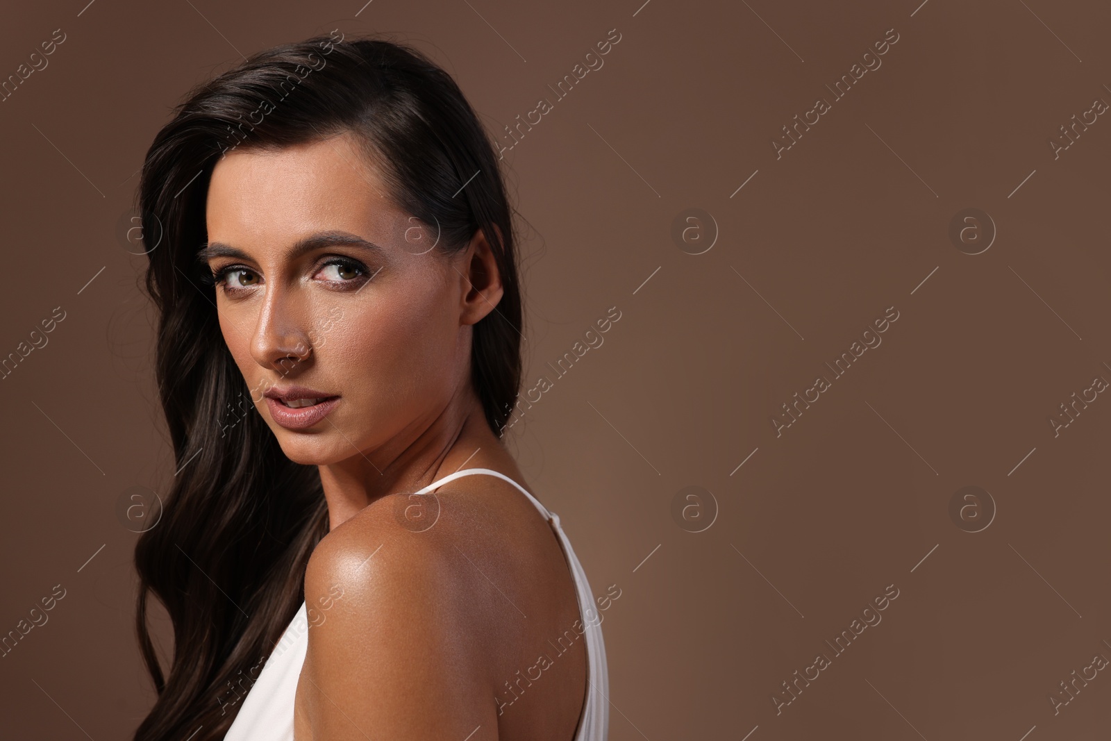 Photo of Hair styling. Beautiful woman with wavy long hair on brown background, space for text