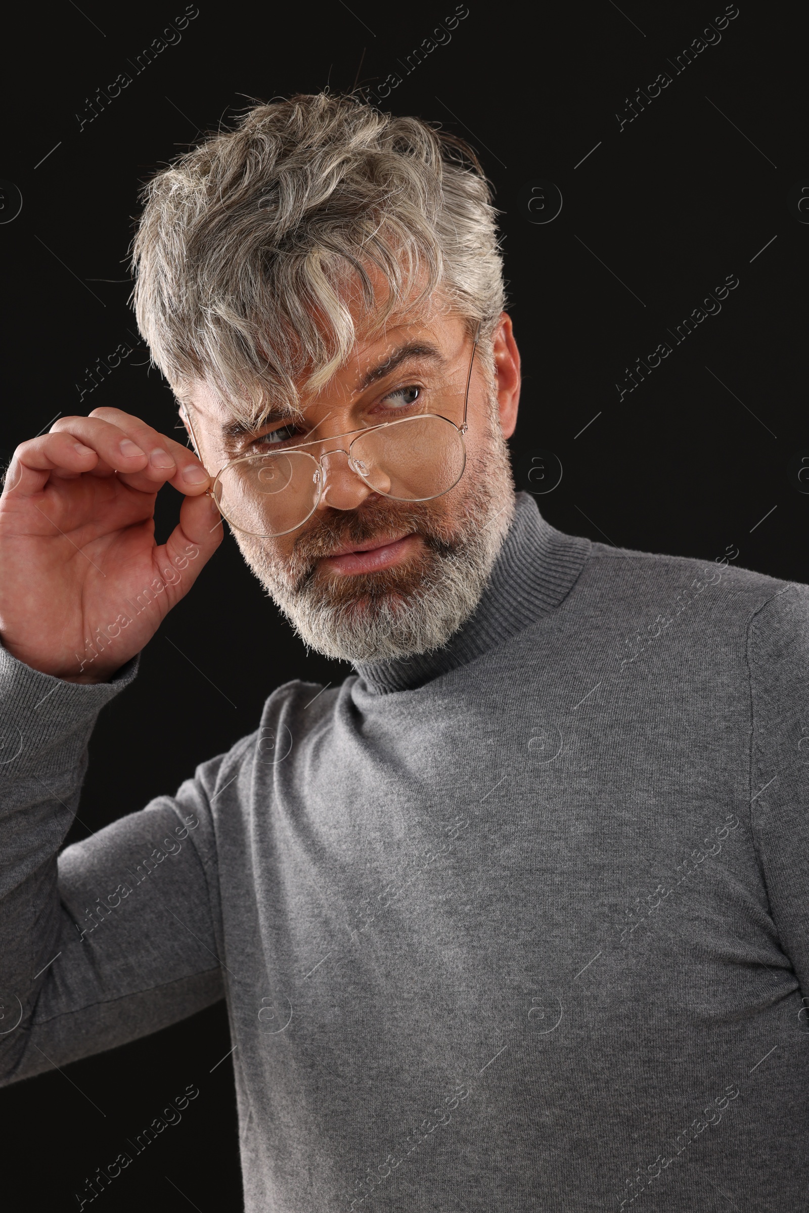 Photo of Portrait of confident man with beautiful hairstyle on black background