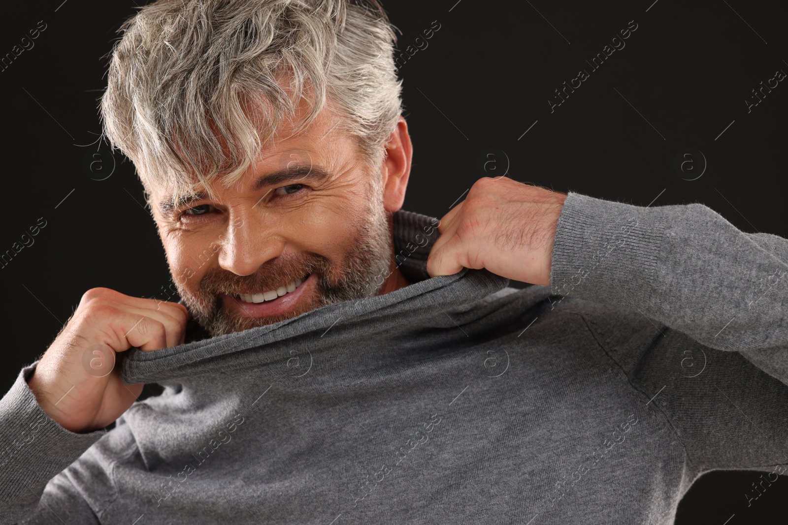 Photo of Portrait of smiling man with beautiful hairstyle on black background