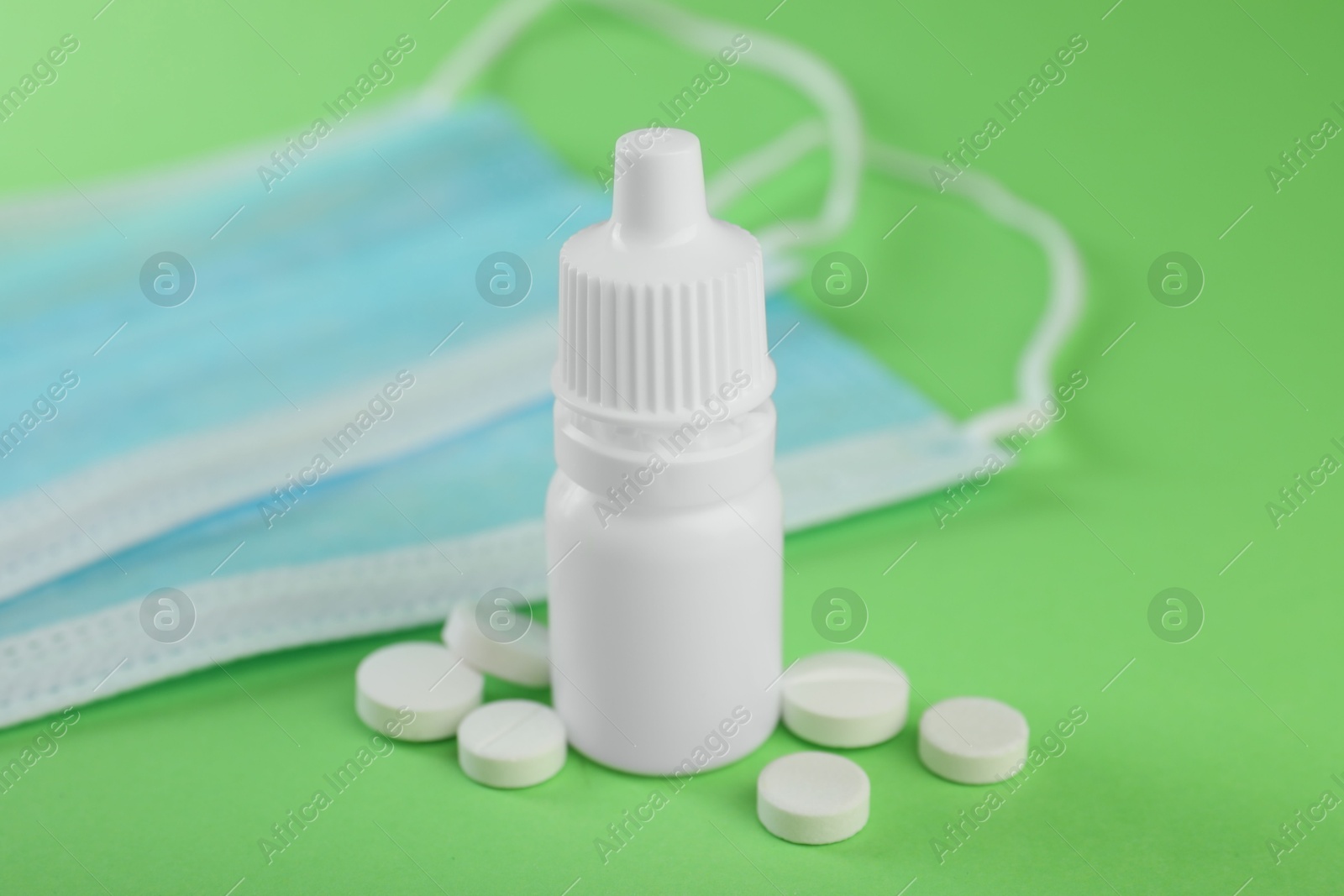 Photo of Allergy treatment. Nasal drops, protective masks and pills on green background, closeup