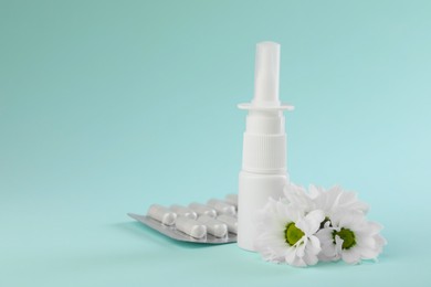 Photo of Allergy treatment. Nasal spray, pills and flowers on light blue background. Space for text