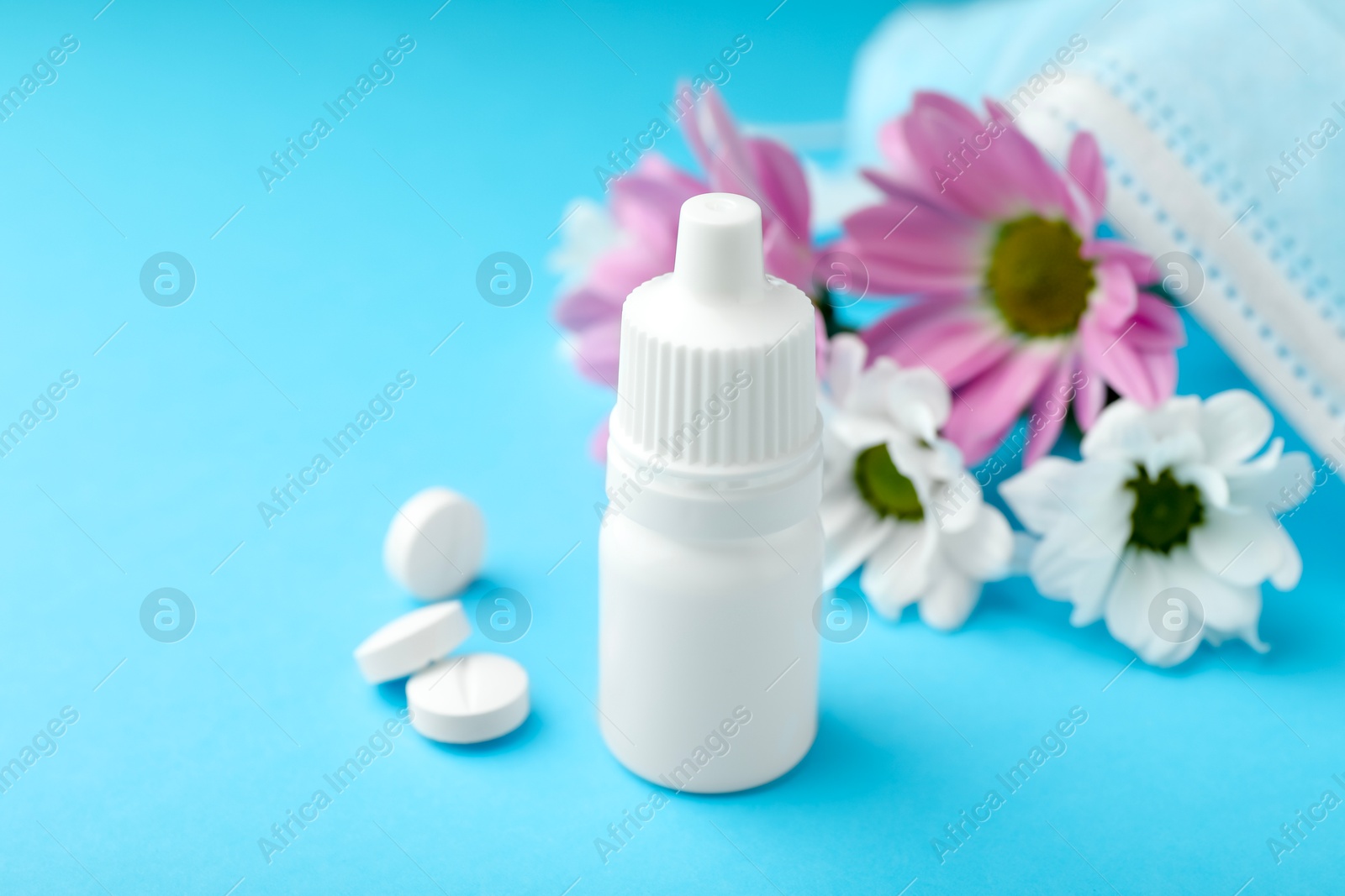 Photo of Allergy treatment. Nasal drops, pills and flowers on light blue background, closeup. Space for text