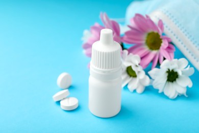 Photo of Allergy treatment. Nasal drops, pills and flowers on light blue background, closeup. Space for text