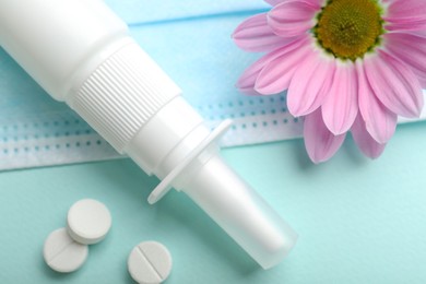 Photo of Allergy treatment. Nasal spray, pills and flower on light blue background, closeup