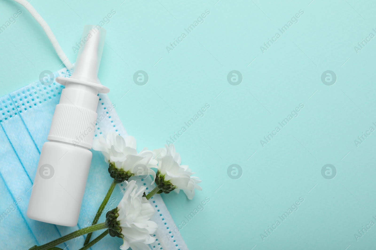 Photo of Allergy treatment. Nasal spray, protective mask and flowers on light blue background, flat lay. Space for text