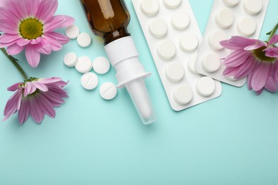 Photo of Allergy treatment. Nasal spray, pills and flowers on light blue background, flat lay. Space for text