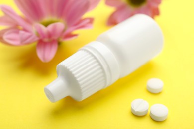 Photo of Allergy treatment. Nasal drops, pills and flowers on yellow background, closeup