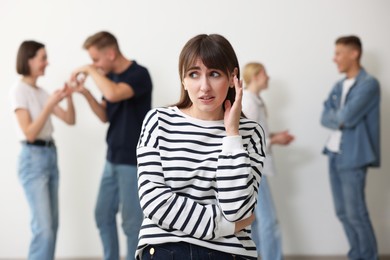 Photo of Young woman feeling uncomfortable among people indoors, selective focus