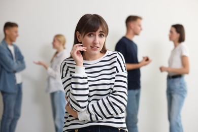 Photo of Young woman feeling uncomfortable among people indoors, selective focus