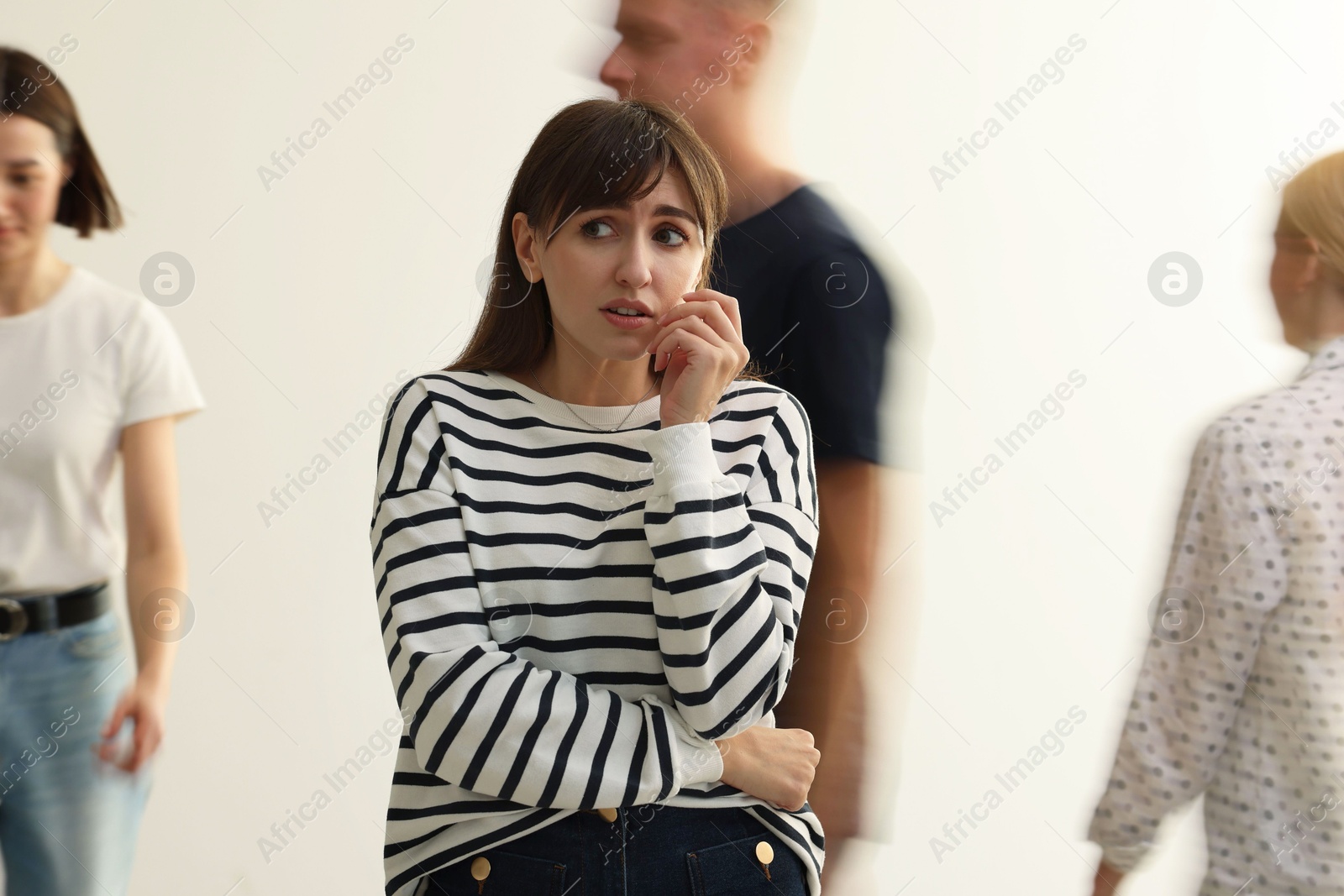 Photo of Young woman feeling uncomfortable among people indoors