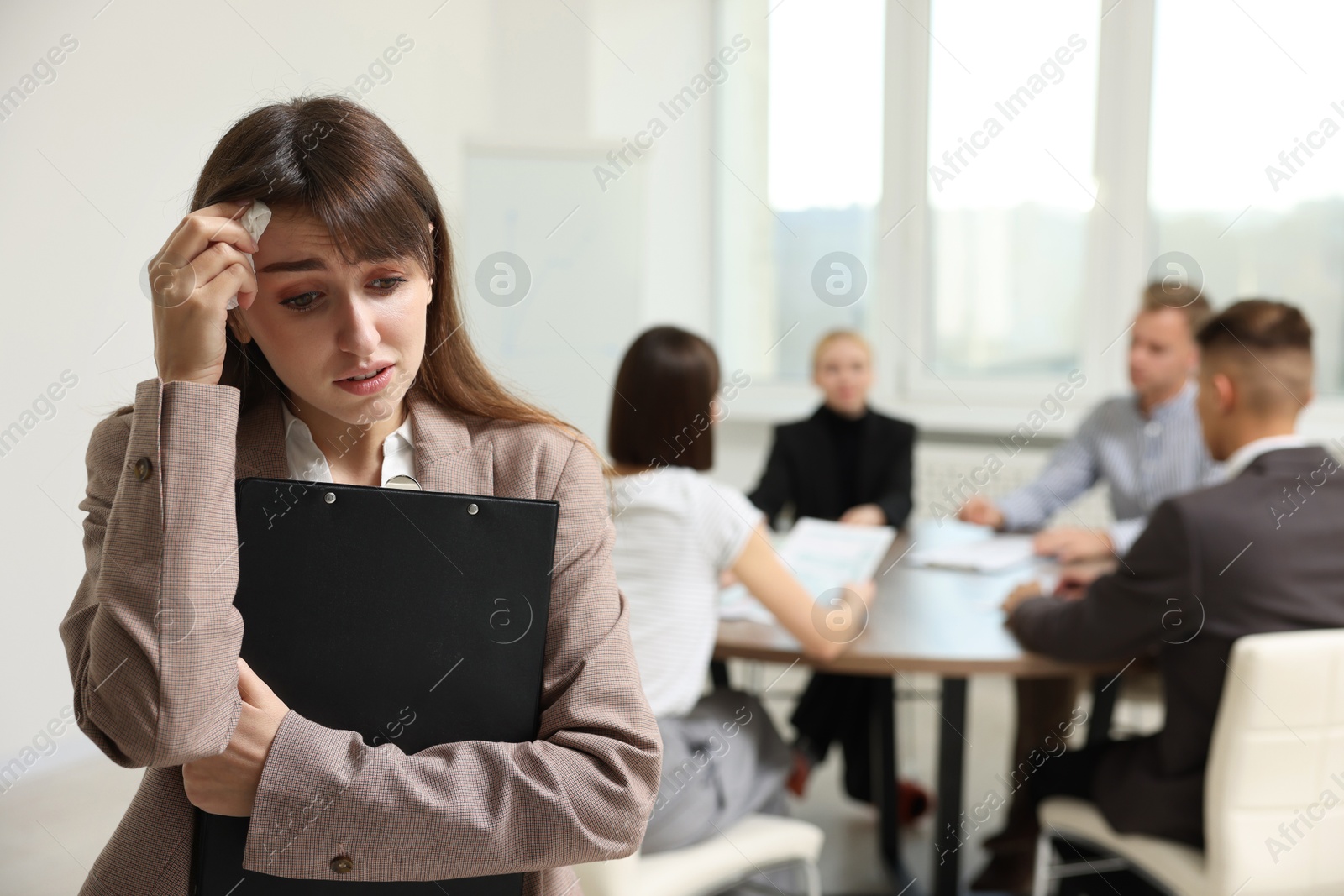 Photo of Glossophobia. Woman with paper tissue and clipboard feeling embarrassed during business meeting in office, selective focus