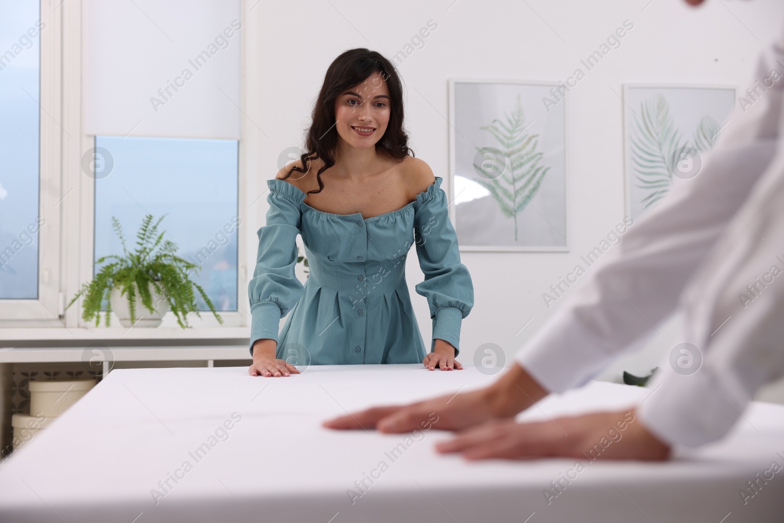 Photo of Couple putting white tablecloth on table at home