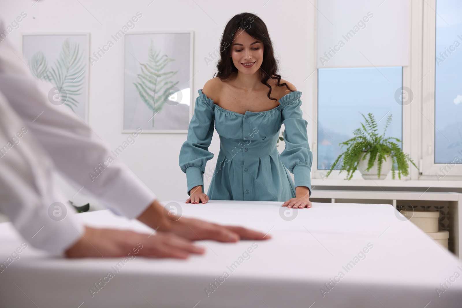 Photo of Couple putting white tablecloth on table at home