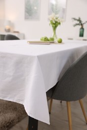 Photo of Table with white tablecloth and chair indoors, closeup