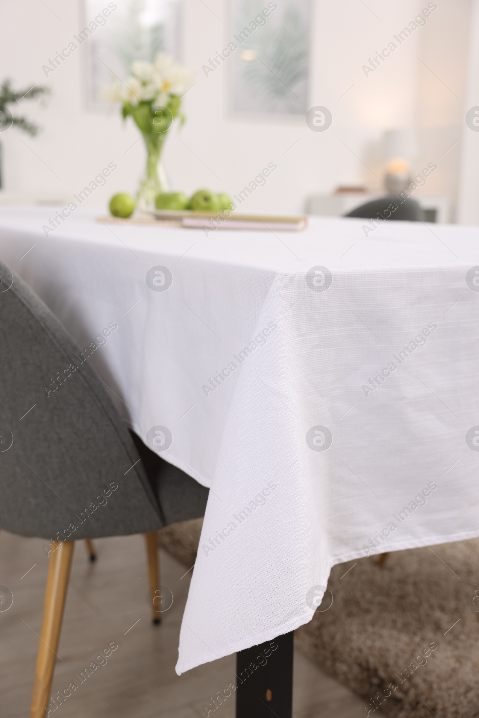 Photo of Table with white tablecloth and chair indoors, closeup