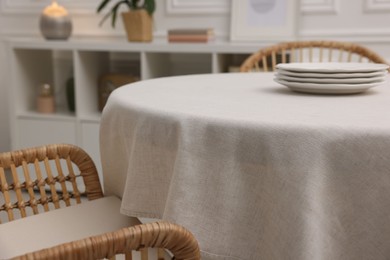 Photo of Table with white tablecloth and plates in room, closeup