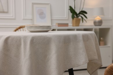 Photo of Table with white tablecloth and plates in room, closeup