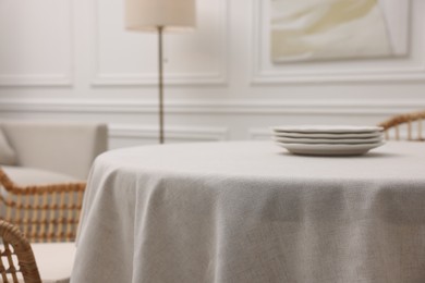 Photo of Table with white tablecloth and plates in room, closeup