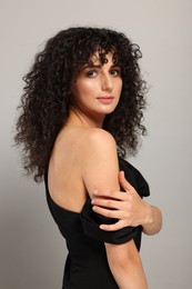 Photo of Beautiful young woman with long curly hair on light grey background