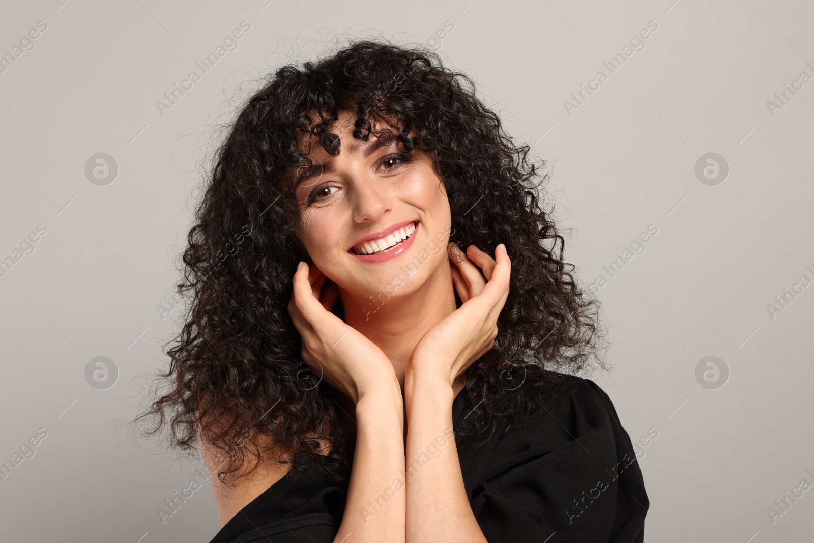 Photo of Beautiful young woman with long curly hair on light grey background