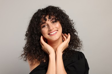 Photo of Beautiful young woman with long curly hair on light grey background