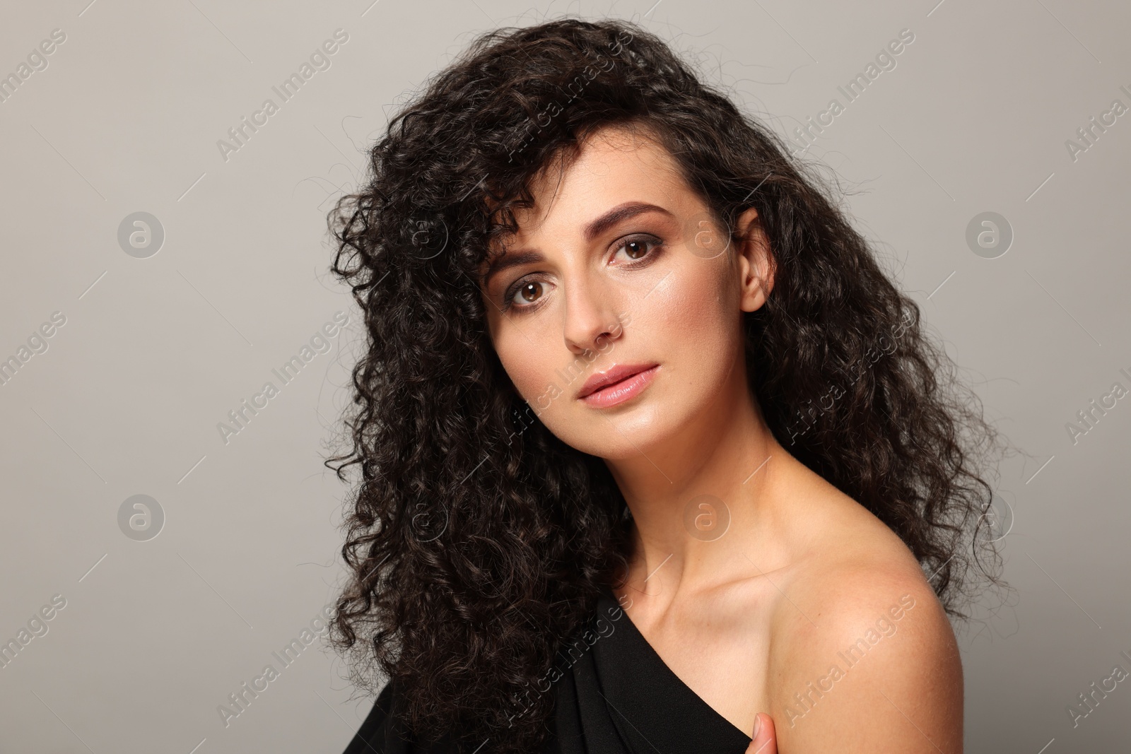 Photo of Beautiful young woman with long curly hair on light grey background