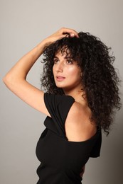 Photo of Beautiful young woman with long curly hair on light grey background