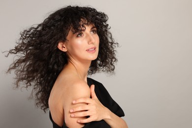 Photo of Beautiful young woman with long curly hair on light grey background