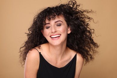 Photo of Beautiful young woman with long curly hair on beige background