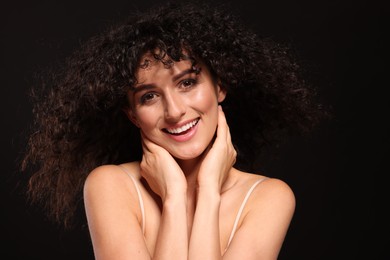 Photo of Beautiful young woman with long curly hair on black background