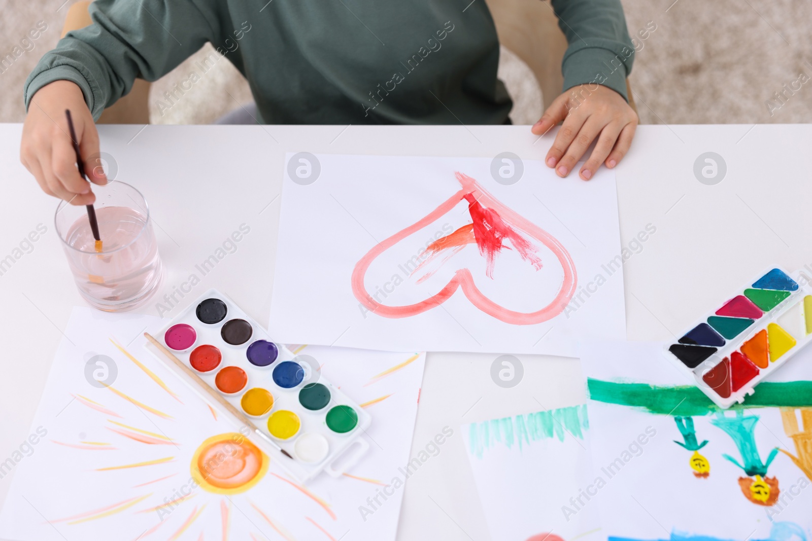 Photo of Little boy drawing at white table indoors, closeup