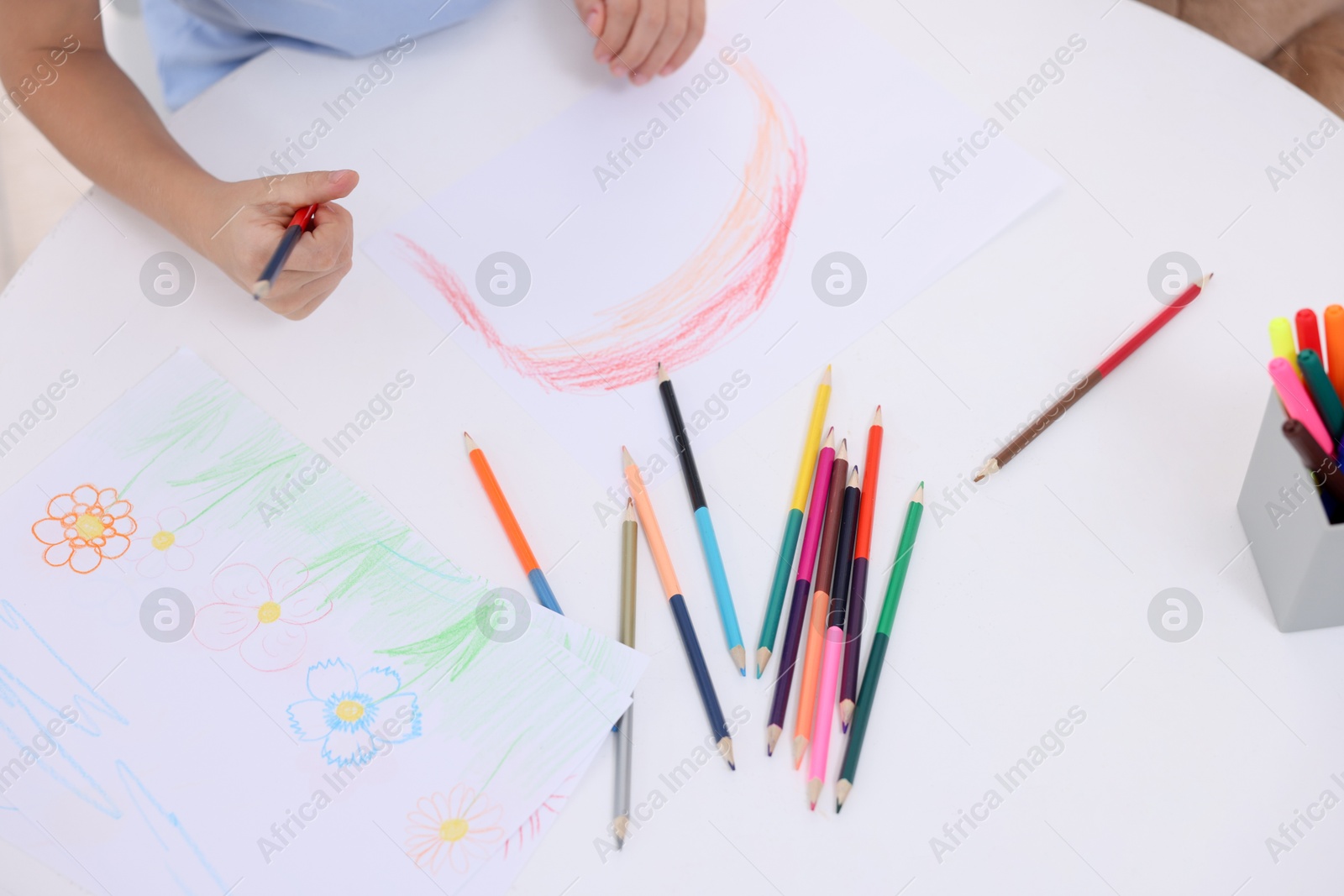 Photo of Boy drawing rainbow at white table, above view