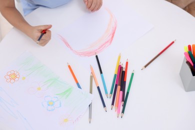 Photo of Boy drawing rainbow at white table, above view