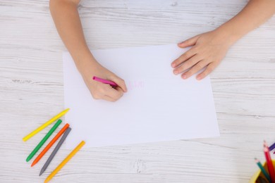 Photo of Boy drawing picture at light wooden table, top view