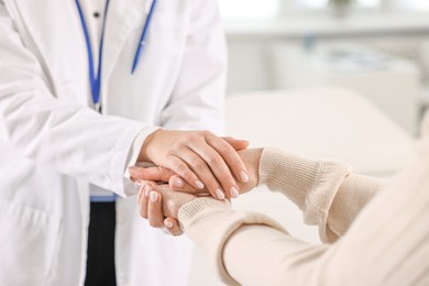 Photo of Doctor supporting patient during appointment in hospital, closeup of hands