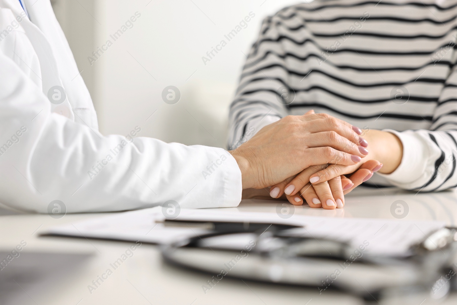 Photo of Doctor supporting patient during appointment in hospital, closeup of hands