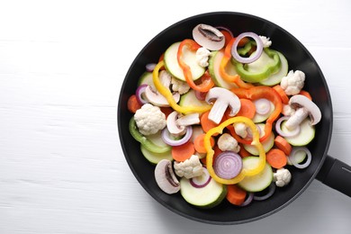 Photo of Frying pan with mix of vegetables and mushrooms on white wooden table, top view. Space for text