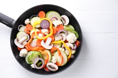 Photo of Frying pan with mix of vegetables and mushrooms on white wooden table, top view. Space for text