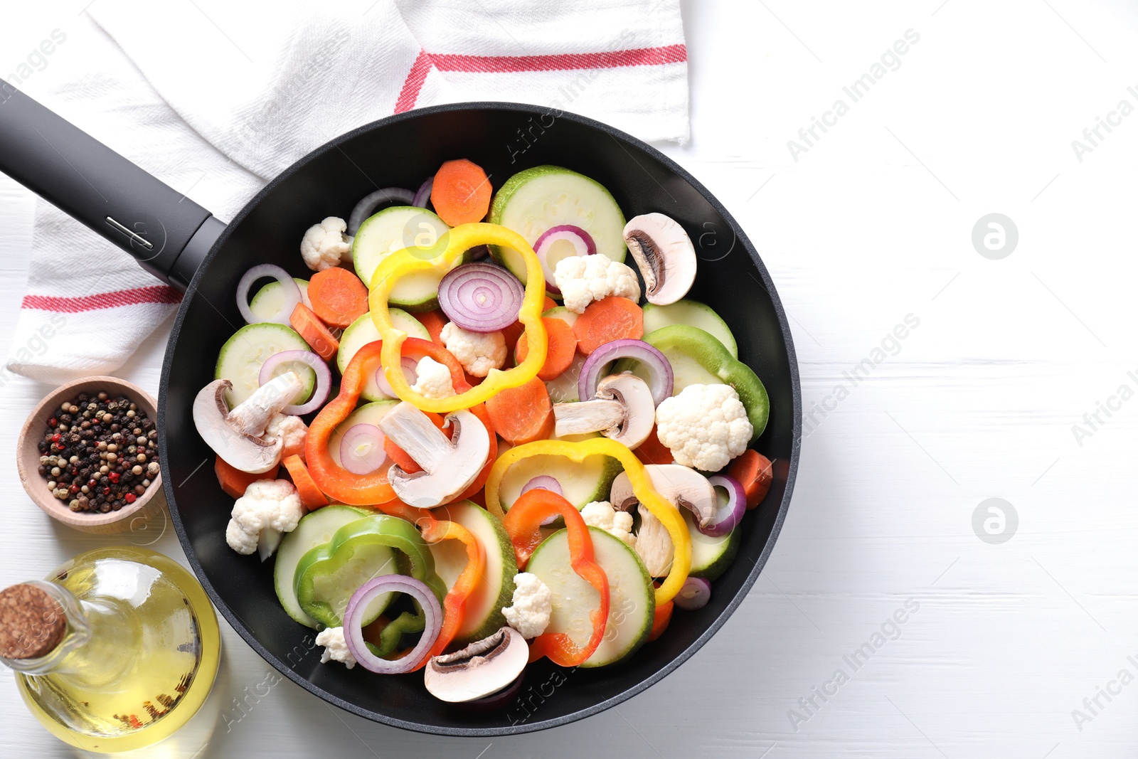 Photo of Frying pan with mix of vegetables, mushrooms and spices on white wooden table, top view. Space for text