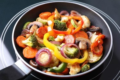 Photo of Frying pan with mix of vegetables and mushrooms on cooktop, closeup